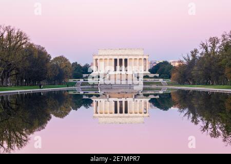 Ein rosafarbener Himmel und das ikonische Lincoln Memorial aus elfenbeinfarbenem Marmor spiegeln sich an einem frischen Herbstmorgen in Washington, DC, im reflektierenden Pool. Befindet sich im Stockfoto