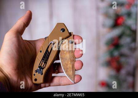 Faltbares Jagdmesser in der Hand auf buntem Hintergrund Stockfoto