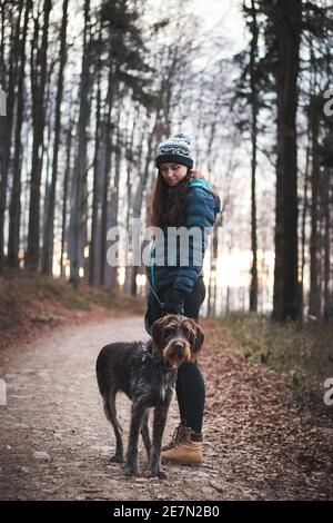 Faszinierte Gesicht einer braunen weiblichen Bohemian Wire-haired zeigt Griffon. Besitzer in Winterkleidung mit einem leichten Lächeln. Das Konzept der Beziehung Stockfoto