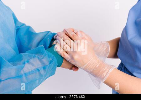 Ein vergrößertes Foto der Hände, in denen ein Arzt in Handschuhen die Hände des Patienten als Zeichen der Unterstützung hält. Zurückgeben, ehrenamtlich und sozial Stockfoto