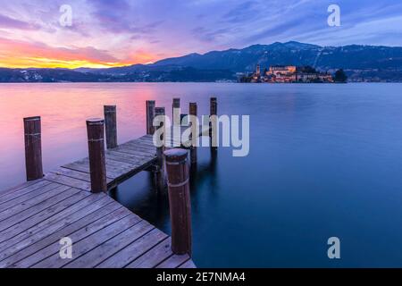 Sonnenuntergang in der Nähe einer Anlegestelle vor der Insel San Giulio und dem Ortasee. Orta San Giulio, See Orta, Provinz Novara, Piemont, Italien. Stockfoto