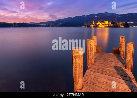 Sonnenuntergang in der Nähe einer Anlegestelle vor der Insel San Giulio und dem Ortasee. Orta San Giulio, See Orta, Provinz Novara, Piemont, Italien. Stockfoto