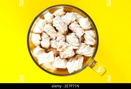 Kakao Getränk mit Marshmallows und Schokoladenpulver in Glas Becher Auf gelbem Hintergrund Draufsicht Stockfoto