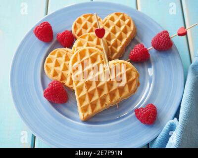 Belgische Waffeln in Herzform mit Himbeeren. Valentinstag Hintergrund. Stockfoto