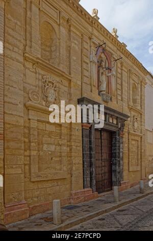 Ein großes mittelalterliches Haus mit seiner dekorativen Fassade in einer schmalen dekorativ gepflasterten Straße in der Hügelstadt Antequerra in Andalusien. Stockfoto