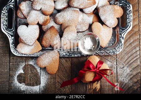 Herzförmige Shortbread-Kekse mit Puderzucker bestreut auf einem Tablett Stockfoto