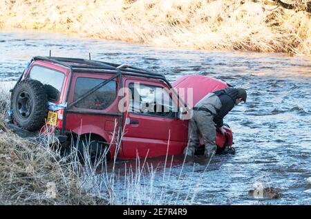 **BITTE BEACHTEN SIE DAS KORREKTE DATUM** River Rescue West Lothian, Schottland, UK. Januar 2021. Ein Mann holt sich ein Suzuki Jimny Fahrzeug mit Hund an Bord vom River Almond, West Lothian, Schottland. Quelle: Ian Rutherford/Alamy Live News. Stockfoto