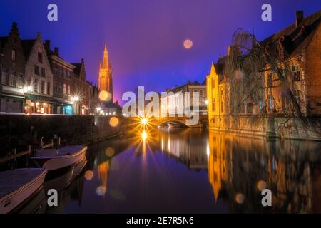 Ikonische märchenhafte Ansicht der Kanäle von Brügge, während des Regens. Nepomucenusbrücke und Kirche unserer Lieben Frau Brügge im Hintergrund. Belgien Stockfoto