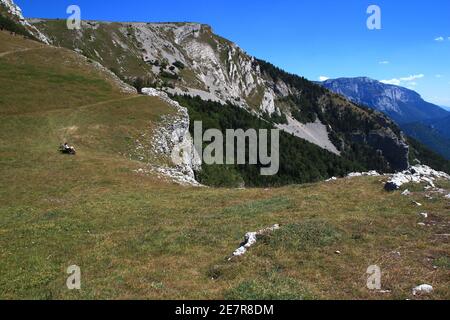 Ein Wanderer blickt auf die spektakuläre Aussicht auf die Region Diois, während er sich auf einer Bank in der Nähe des Plateau de Beure (Vercors, Frankreich) Stockfoto