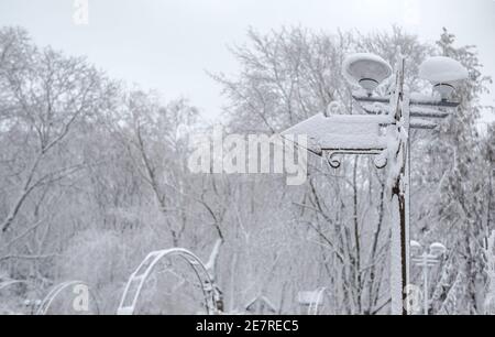 Schneebedeckter Wegweiser mit Laterne auf dem Hintergrund von Bäumen im Schnee. Stockfoto