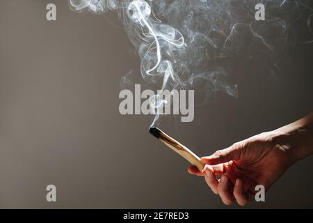 Weißer Rauch kommt von Palo santo Holzstab in der Hand gehalten. Stockfoto