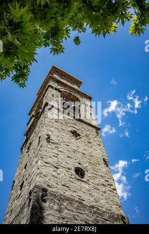 Frühling Straße niedrigen Winkel Ansicht, Stein Glockenturm, Baum Zweig und Himmel von der Stadt Metsovo, Epirus, Griechenland. Das Hotel ist ein beliebtes griechisches Winterskigebiet mit alten Häusern im Balkan-Stil Stockfoto