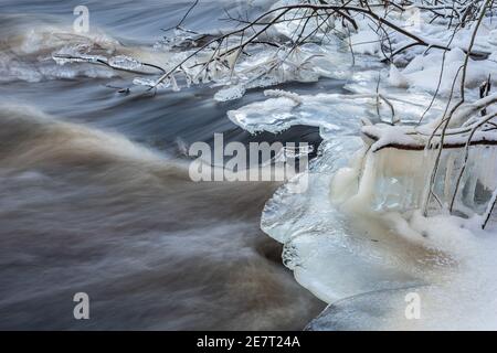 Der Fluss, der in einem kalten Winter auf Äste trifft Tag und bildet schöne Eisformationen Stockfoto