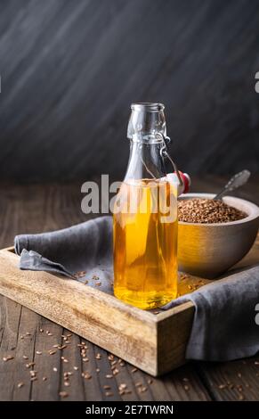 Leinsamenöl in einer Glasflasche, verziert mit ganzen Samen auf rustikalem Holzhintergrund mit Kopierraum Stockfoto