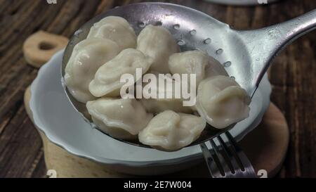 Appetitlich gekochte Knödel, Gießen Knödel in einen Teller aus einer Metalllöffel. Stockfoto