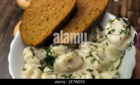 Draufsicht Knödel mit Kräutern bestreut, hausgemachtes Essen, Knödel auf einem Teller auf einem Holztablett, appetitliches Essen, Kochen in der Küche. Stockfoto