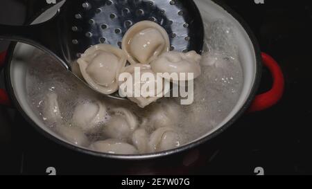 Knödel in einem Topf kochen, hausgemachte Knödel. Die Knödel mit einer Messlöffel umrühren. Stockfoto