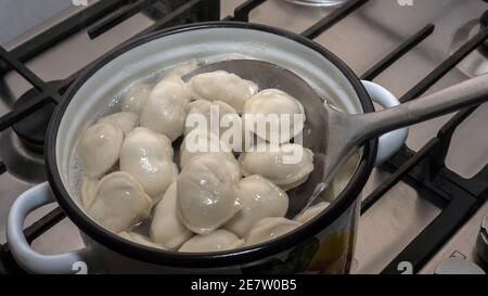 Appetitlich gekochte Knödel, Gießen Knödel in einen Teller aus einer Metalllöffel. Stockfoto