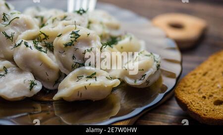 Hausgemachte Knödel in einem Teller auf einem Holztablett, Knödel auf einer Gabel, leckeres Essen. Stockfoto