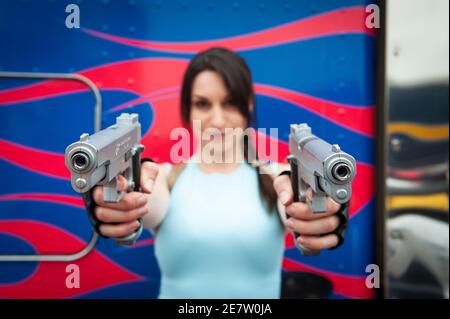COS-Spieler verkleidet als Lara Croft hält 2 Gewehre bis zur Kamera, auf der London Comic Con, Juli 2014. Stockfoto