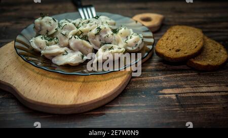 Hausgemachte Knödel in einem Teller auf einem Holztablett, Knödel auf einer Gabel, leckeres Essen. Stockfoto