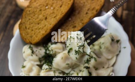 Knödel in einem schönen Teller auf einem Holztablett, Nahaufnahme von Knödeln mit Kräutern. Stockfoto