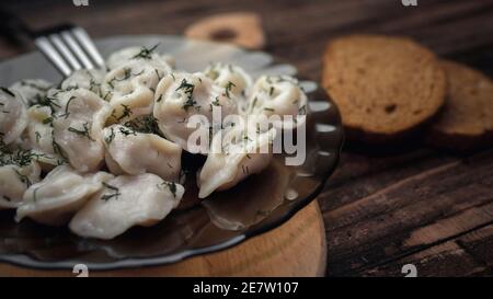 Köstliche Knödel in einem Teller auf einem hölzernen Tablett, Dillknödel, hausgemachte Speisen, ein Gericht auf einem Teller. Stockfoto