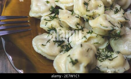 Russische Knödel mit Kräutern, hausgemachte Knödel in einem Teller mit Dill verziert, hausgemachte Speisen. Stockfoto