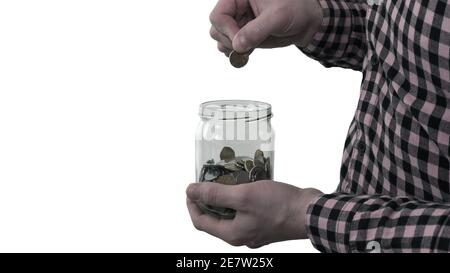 Mann wirft eine Münze in ein Sparschwein in einem Glas isoliert auf einem weißen Hintergrund. Der Mann hat ein finanzielles Problem. Münzen in der Bank. Sparen Sie Geld Stockfoto