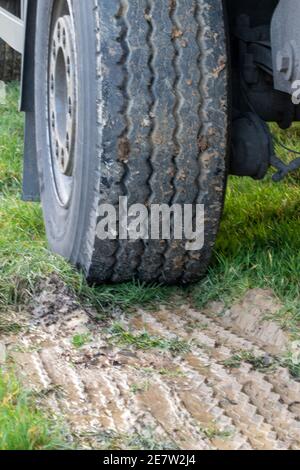 Der Reifen eines LKW mit einem guten Profil. Davor der Abdruck der Reifenspur im Schlamm. Stockfoto