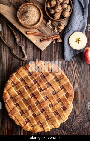 Hausgemachtes Dessert, altmodischer Gitterkrustenkuchen mit geriebener Apfel- und Walnussfüllung, bestreut mit Granulatzucker und Zimt auf rustikalem Holz Stockfoto