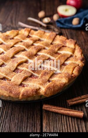 Hausgemachtes Dessert, altmodischer Gitterkrustenkuchen mit geriebener Apfel- und Walnussfüllung, bestreut mit Granulatzucker und Zimt auf rustikalem Holz Stockfoto