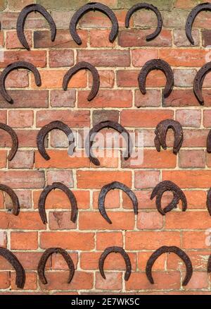 Hufeisen Hintergrund, Reihen von alten Hufeisen auf einer Ziegelwand, Großbritannien Stockfoto