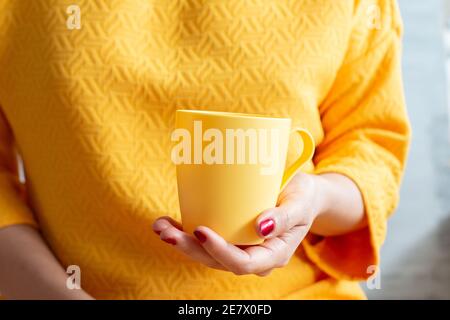 Frau in gelber Farbe Kleid hält eine Tasse Tee Stockfoto