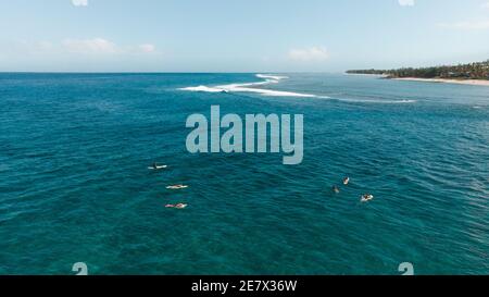 Atemberaubende Aussicht auf junge Surfer, die in einem türkisfarbenen Meer surfen An einem sonnigen Sommertag Stockfoto