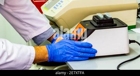 Laborwissenschaftler, der die Thermoschüttler-Maschine mit DNA- oder RNA-Probe in Röhrchen einsetzt. Dieses Gerät eignet sich für Anwendungen in der Molekularbiologie Stockfoto