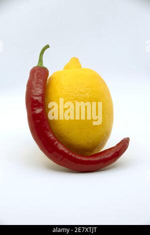 Gelbe Zitrone mit bitterrotem Pfeffer auf weißem Hintergrund. Stockfoto