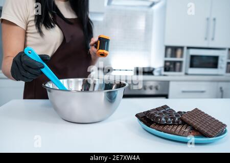 Nahaufnahme der weiblichen Temperaturmessung von geschmolzener Schokolade mit Pyrometer Stockfoto
