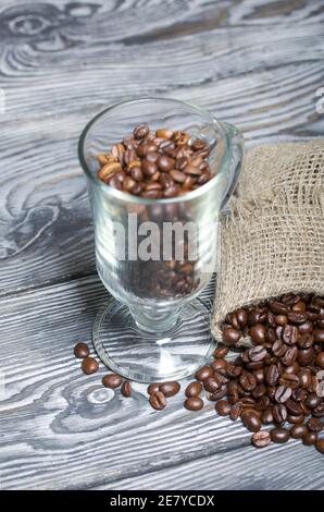Kaffeebohnen. In einen Glaskelch und einen Leinenbeutel gegossen. Nahaufnahme. Stockfoto