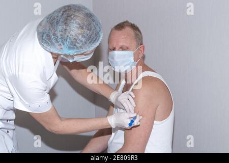 Impfung gegen Coronavirus. Eine Krankenschwester gibt einem Mann eine Injektion mit dem Covid-19-Impfstoff. Infektionsprävention. Stockfoto