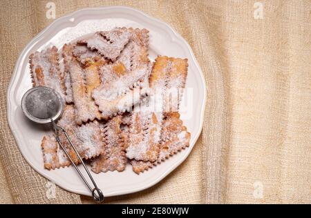 Italienische Süßigkeiten. Traditionelle Karnevalsbonbons, chiacchiere auf weißem Teller. Blick von oben. Speicherplatz kopieren. Stockfoto