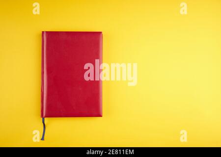 Leeres rotes Ledertagebuch auf gelbem trendigen Hintergrund. Kopierraum. Draufsicht Stockfoto