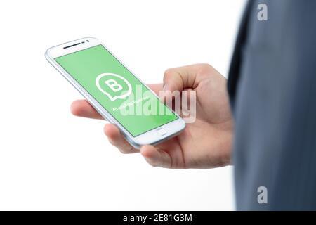 ROSARIO, ARGENTINIEN - 30. JANUAR 2021: WhatsApp Business-Anwendung auf dem Bildschirm eines Smartphones. Junger Geschäftsmann mit einem weißen Handy in der Hand. Stockfoto