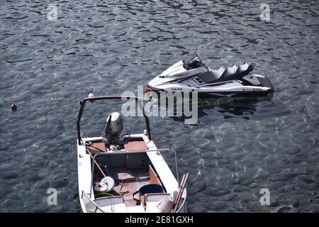 Kreta oder Kreta, Griechenland - 10. September 2017: Ein angedockter oder geparkter weißer Jet-Ski und ein Motorboot, das auf sauberem Wasser schwimmt oder angedockt ist Stockfoto