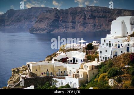 Santorini, Griechenland: Weitwinkel-Luftaufnahme der Stadtlandschaft mit weißen Häusern, die im Sommer auf Bergen gegen Strand und Berge gebaut wurden Stockfoto