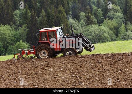 Klaebu, Norwegen - 23. Mai 2014: Ein kleiner rot bedeckter Traktor Quicke 540 pflügt das Feld. Stockfoto