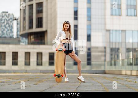 Junge Frau mit Longboard im Urlaub. Stockfoto