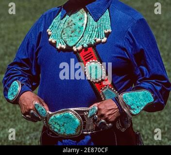 Dieser prächtige Türkis- und Silberschmuck wurde von einem Zuni Pueblo Indianer in Albuquerque, New Mexico, USA, hergestellt und getragen. Die farbenprächtigen blau-grünen Halbedelsteine in verschiedenen Formen und Größen wurden vom indischen Kunsthandwerker zu einer auffälligen Halskette, Armbändern, Ringen, einer Gürtelschnalle und einem Bandolier über der Brust gefertigt. Türkisschmuck ist eine Kunstform, die die Kreativität und Kultur der Indianer im Laufe der Jahrhunderte widerspiegelt, insbesondere Mitglieder von drei Indianerstämmen im Südwesten der USA, den Navajo, Hopi und Zuni. Stockfoto