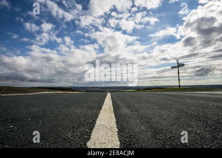 Niedriger Blick auf eine leere Straße in der Nähe von Goathland im North York Moors National Park, mit einem altmodischen Straßenschild am Straßenrand Stockfoto