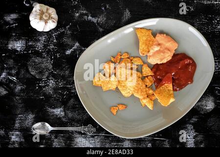 Mexikanische Mais-Chips Nachos mit Salsa und Käse Dip / Mais Tortilla Chips mit würziger Sauce auf dunklem Holzbrett Stockfoto